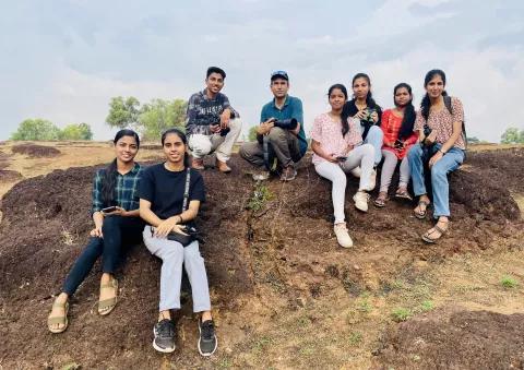 Students and a teacher sitting on a hill