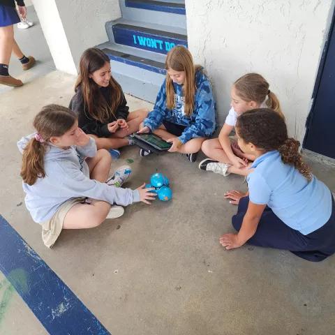 a group of girls working with a robot