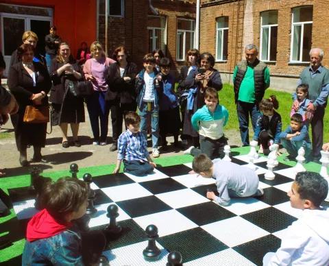 a group of people gathered around a large chess board