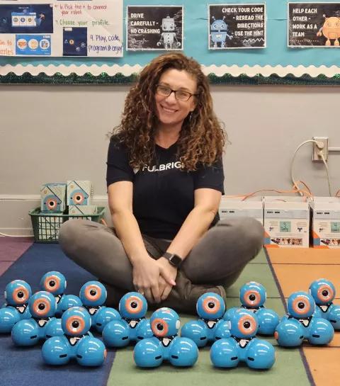 a teacher posing with blue robots