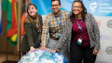 three people in front of a globe with the words Global Teaching Dialogue