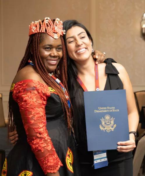 two women holding a certificate from the U.S. Department of State