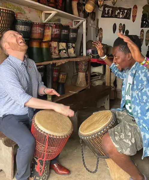 two men laughing and playing African drums