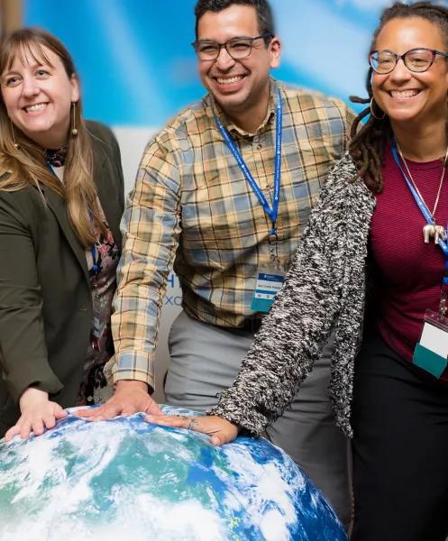 Three teachers standing in front of a globe