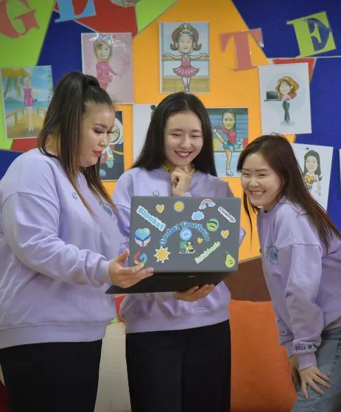 Three teachers standing in front of a laptop